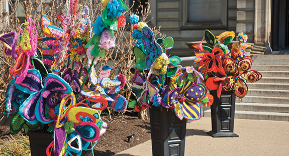 Recent snow flurries have made it easy to forget that it really is April. But the colorful Pop des Fleurs in front of the steps of Oakland’s Carnegie Library serve as a promise of warmer days ahead. Made from colorful acrylic yarn, the flowers grew out of an idea conceived by a Fiberarts Guild of Pittsburgh member during the cold and dreary Pittsburgh winter of 2013-14. Soon, blasts of color appeared in front of the Carnegie Library. Pop des Fleurs then became a Community Outreach Project of the guild’s Fiberart International 2016 being held in Pittsburgh. The project has several partners—including Pitt—who have made and placed displays at 16 other locations around the city. (Photo by Emily O'Donnell)